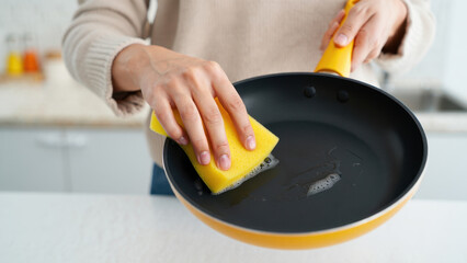Washing nonstick pan with sponge and soap, showing wrong cookware care, coating damage, harsh cleaning agents, scratched surface, kitchen routine, hand wash, household habits, kitchen hygiene tips