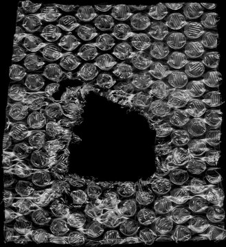 Ripped bubble wrap with a large hole in the center, showcasing fragility and protection.