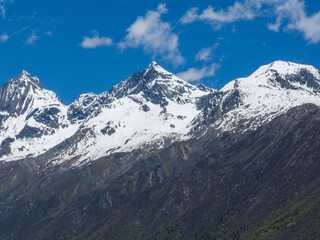 Aerial view of beautiful high altitude snow capped mountain and forest landscape