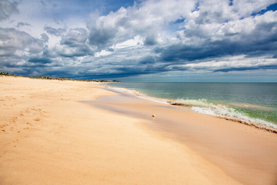 A breathtaking panoramic view of Meia Praia beach in Lagos, Algarve, Portugal, showcasing its expansive golden sands stretching into the distance under a vibrant blue sky 