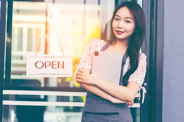 Female owner of coffee shop or restaurant turning round sign to open. Smiling young asian woman owner, employee retail coffee shop woman hand in setting sign board to open for welcome customer, reopen