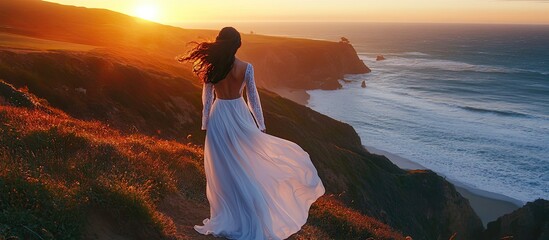 Woman in White Dress Gazing at Sunset Over Coastal Cliffs and Ocean