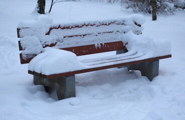 A snow-covered street bench after a snowfall
