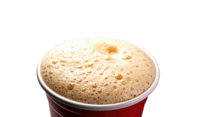 Close-up of frothy beverage in a red cup against a stark black background