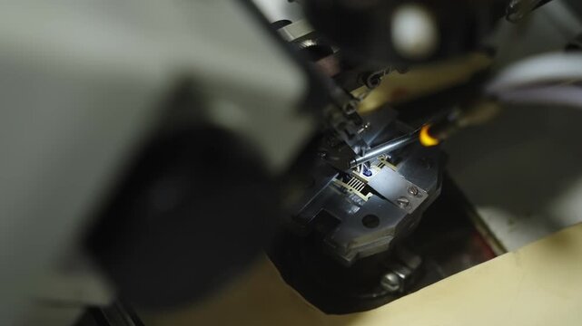 Close-up of wire bonding on a microchip under a microscope, with bonding tool aligning to die pads and leads during semiconductor assembly for microelectronics manufacturing