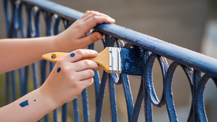 Hand painting a blue metal railing with paintbrush for home improvement and diy projects