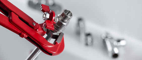 Plumbing tools and fittings. Closeup of plumber wrench holding water valve with pipe. banner with copy space