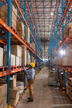 African American man wearing helmet scanning boxes with barcode scanner in warehouse, copy space