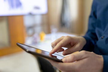 African American male holding tablet and tapping touchscreen in office lounge near monitor