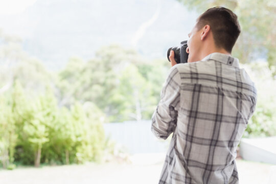 Man capturing lush garden with DSLR camera while standing on backyard deck, copy space