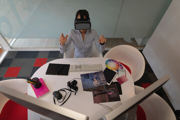 Woman making mid-air gestures using virtual reality headset at office desk with drawing tablet