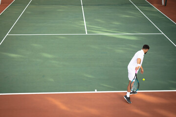 Male athlete hitting forehand at baseline on outdoor tennis court with racket and ball, copy space
