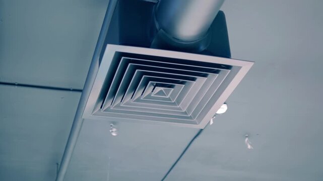 Gray ventilation pipe with a grill near the ceiling in a warehouse building. Shot in motion
