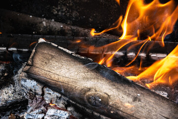 Burning wood logs in bonfire with sparks and glowing heat