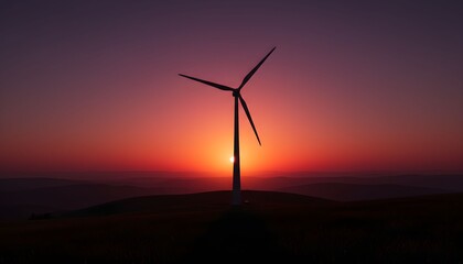 Wind turbine standing on a hill at sunset with a vibrant orange and red sky