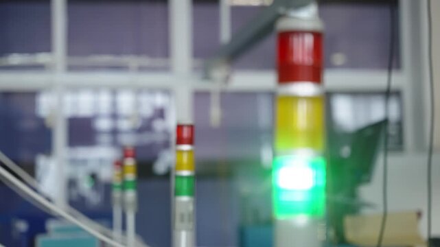 Close-up view of an industrial stack light tower with red, yellow, and green status indicators in a modern factory environment, signaling safety status and production monitoring