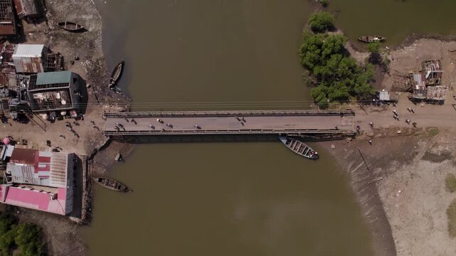 Aerial view of the bridge over muddy waters with shacks and boats along the riverbanks, Quelimane, Zambezia Province, Mozambique.