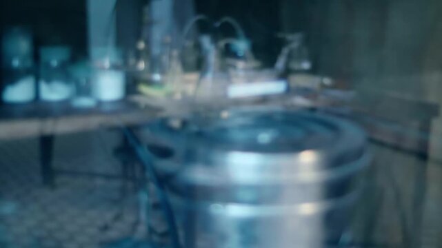 Old style chemistry lab with lots of test tubes, flasks, spirit lamps, chemicals on a table which is reflected in the glass of the cabinet where the medical instrument sterilizer is located. Closeup. 