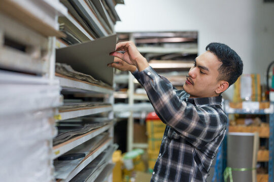 Asian adult man carpenter selecting wood boards for interior design furniture production inside small workshop material store professional tradesman working with wood - Powered by Adobe
