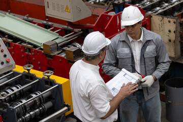 Team of Industrial Engineer in Hard Hats Work at the Heavy Industry Metal Sheet Manufacturing Factory. Factory worker indoors in metal sheet factory. Man working in an industrial factory. 