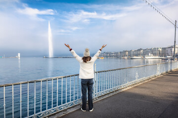Fototapeta premium Rear view of a happy tourist woman looking at the famous Lake Geneva during a moody winter day with fog and sunshine, Switzerland