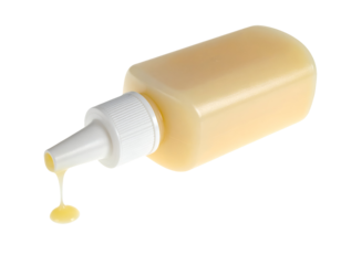 Plastic squeeze bottle dispensing dripping yellow sauce or honey with drop forming cut out on isolated background