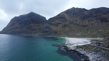 Obraz premium Aerial view of a turquoise mountain lake surrounded by rugged terrain. Clear water contrasting with rocky landscape, photographed from a drone.