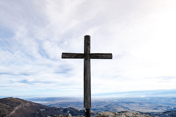 Christian cross on the top of hill, barren field in winter. Holy cross on the hill for pilgrimage,...