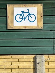 Bicycle sign displayed on a building wall with wooden and brick materials during bright daylight