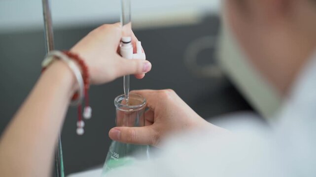 Scientist carefully dispensing liquid into a conical flask using a pipette in a laboratory setting