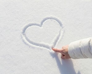 Hand drawing heart in snow close up winter love concept background with copy space
