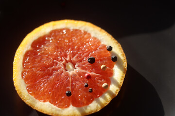 Grapefruit with black pepper on a black background