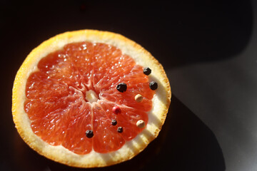 Grapefruit with black pepper on a black background