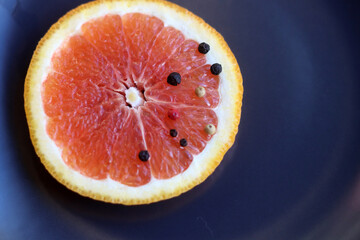 Grapefruit with black pepper on a black background