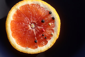 Grapefruit with black pepper on a black background