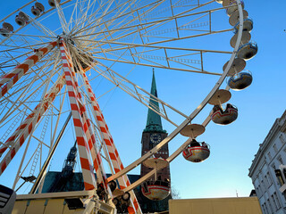 Ferris wheel in city with church and blue sky