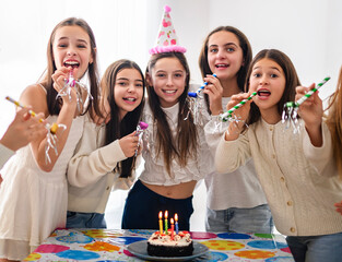 Festive group of preteen pupils aving fun in birthday posing with cake