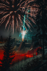Fototapeta premium Fireworks over the city at night. Pyrotechnics with the river and dam. New Year's Eve celebration. Long exposure.