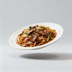 Stir-fried rice noodles with beef and vegetables in a white plate