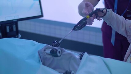 A little girl is learning to become a doctor on a simulator – laparoscopy is a modern method of minimally invasive surgery through small openings - Powered by Adobe