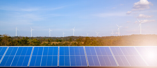 Solar panels park and wind turbines at sunset.Windmill turbines generating green energy electric.Green energy reduce carbon emissions and makes earth cleaner and more ecological.