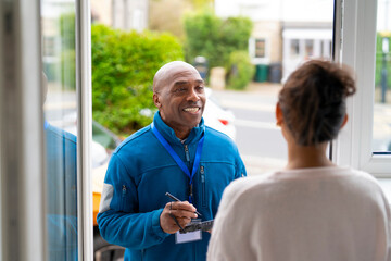 Man at the door smiles while talking to a woman during daytime visit