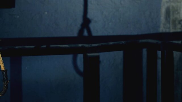 The camera is panning left, to reveal an authentic hanging rope. first we see the shadow inside the hanging chamber, them comes the rope, coated by leather. a 4K video clip.