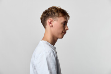 Obraz premium Profile view of a young man in a white shirt against a plain backdrop, conveying calm, focus and minimalism, suitable for lifestyle, fashion, and creative concepts in stock photography