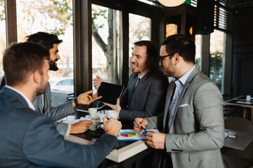 Businessman showing a presentation on a digital tablet to his colleagues during a meeting