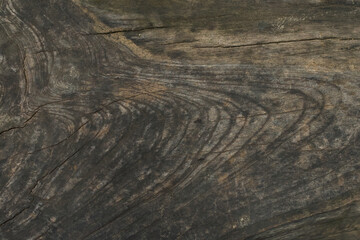 Dark, weathered, richly textured wood grain surface displaying prominent natural swirling patterns and deep cracks.