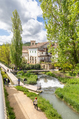 Fototapeta premium Trillo, Spain, Italy - May 05, 2025: Waterfalls running through the town of Trillo in Guadalajara, with tourists strolling around the area in Trillo, Spain.