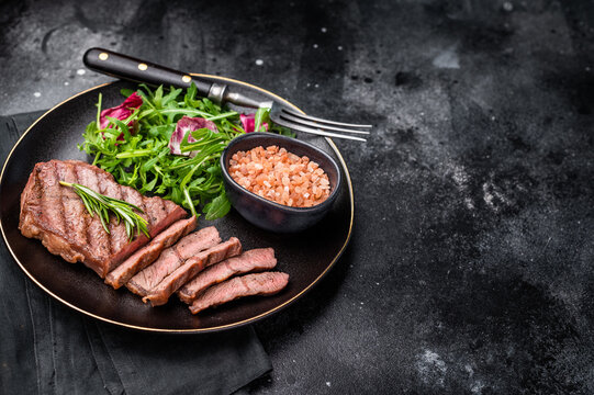 Grilled Top blade steak with salad, beef shoulder meat on a plate. black background. top view