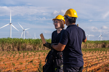 Engineers discuss project plans in a field with wind turbines during the day © Freeday photo