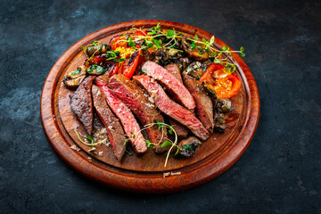 Traditional barbecue grass-fed dry aged roast beef steak tagliata with grilled mushrooms and vegetables cut on wooden board